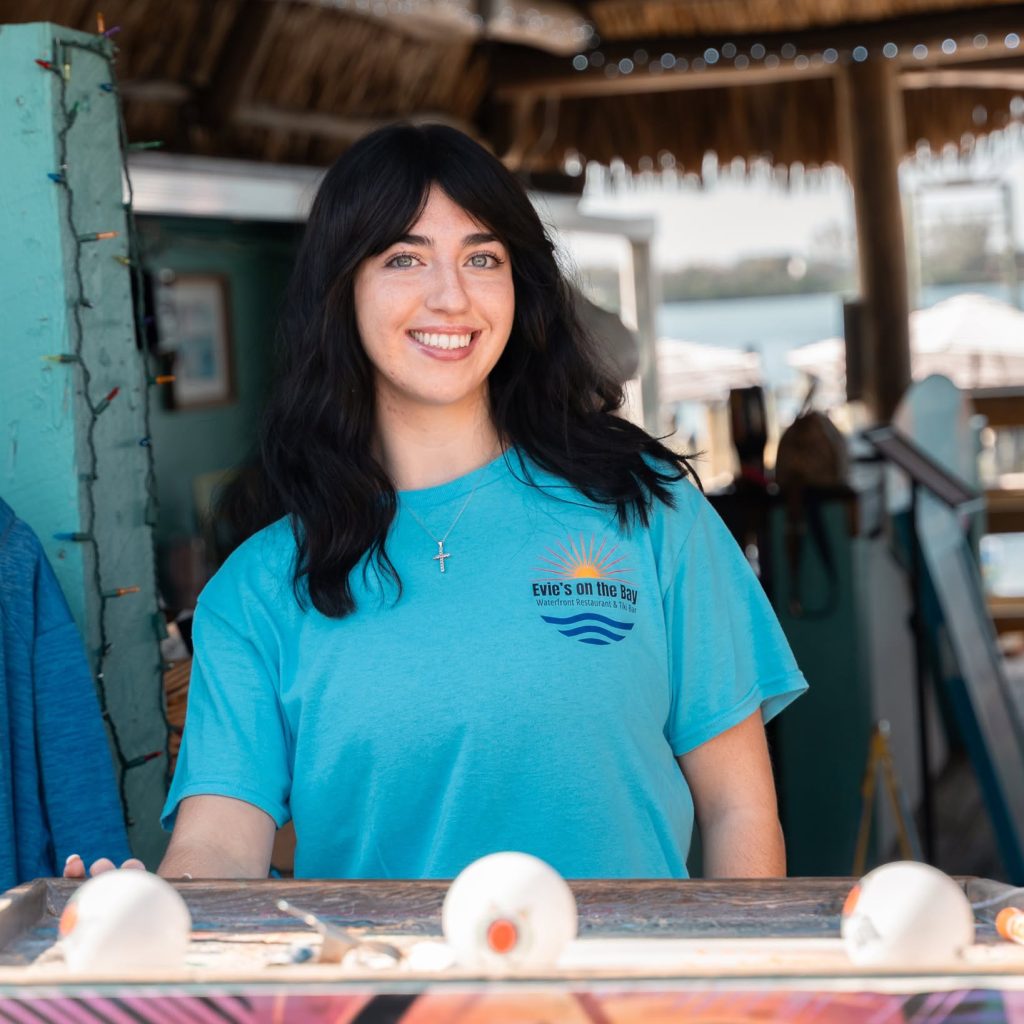 Evie’s on the Bay team member smiling behind the tiki bar.